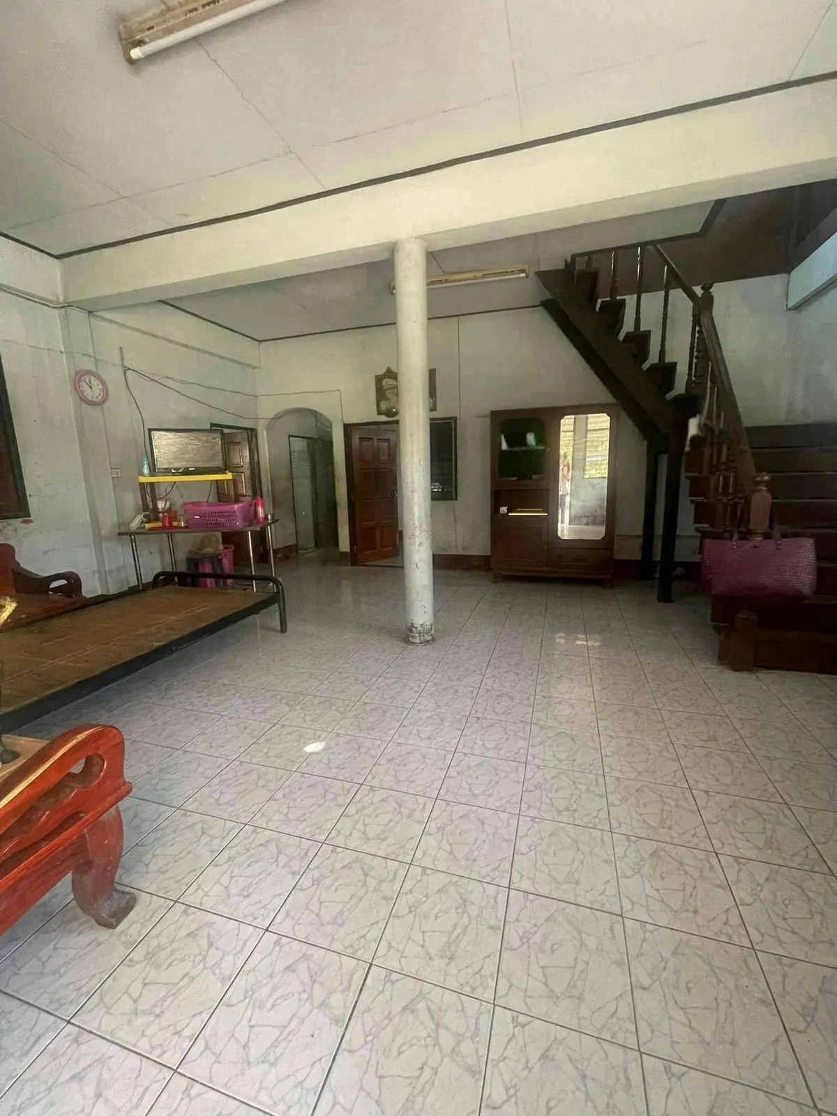 ห้องโถงบ้านเก่าพื้นกระเบื้องสีขาว มีเสาและบันไดไม้